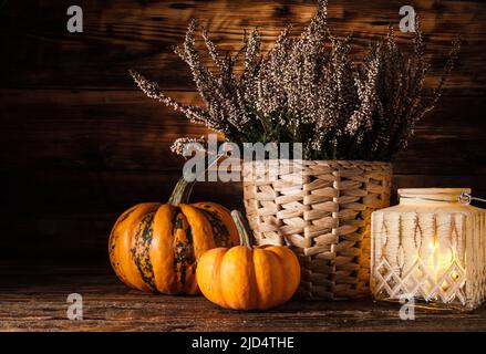Heather flowers, candle and small decorative pumpkins. Autumn or fall composition on a wooden background, for Halloween or Thanksgiving. Stock Photo