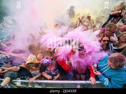 Festival goers throw colored powder at the main stage at Belladrum Tartan Hearts Festival at Inverness, United Kingdom Stock Photo