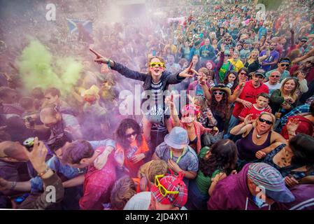 Festival goers throw colored powder at the main stage at Belladrum Tartan Hearts Festival at Inverness, United Kingdom Stock Photo