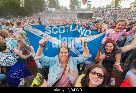 Festival goers throw colored powder at the main stage at Belladrum Tartan Hearts Festival at Inverness, United Kingdom Stock Photo