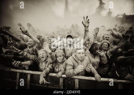 Festival goers throw colored powder at the main stage at Belladrum Tartan Hearts Festival at Inverness, United Kingdom Stock Photo