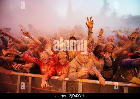 Festival goers throw colored powder at the main stage at Belladrum Tartan Hearts Festival at Inverness, United Kingdom Stock Photo