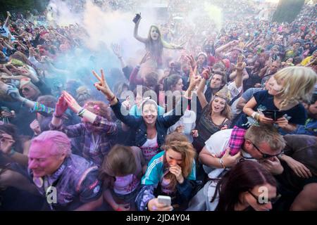 Festival goers throw colored powder at the main stage at Belladrum Tartan Hearts Festival at Inverness, United Kingdom Stock Photo