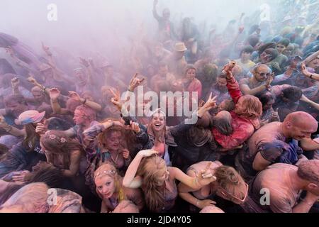 Festival goers throw colored powder at the main stage at Belladrum Tartan Hearts Festival at Inverness, United Kingdom Stock Photo