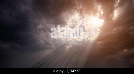 Lowkey dramatic view of sun beams breaking through a dense cumulus cloudscape. Background and inspiration Stock Photo