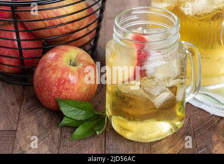 Glass of apple juice, apple slice and ice with fressh red apples on a wooden table Stock Photo