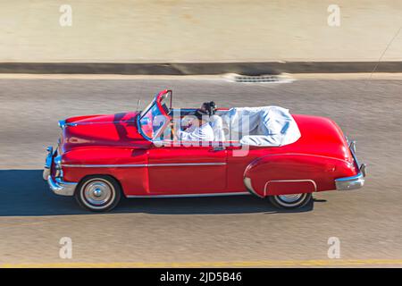A red vintage car drives down the famous Malecon in Havana, Cuba Stock Photo