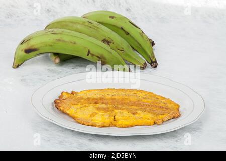 Patacon or toston fried and flattened pieces of green plantain, traditional snack or accompaniment in the Caribbean. Stock Photo