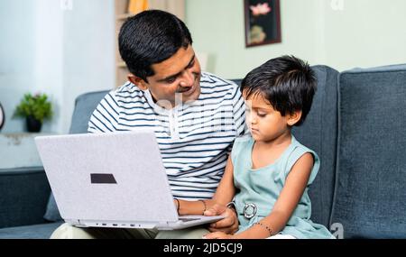 happy Father helping or teaching the daughter to use laptop at home - concept of home schooling, parental teaching and development Stock Photo