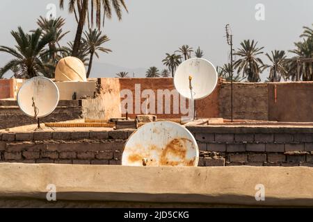 Satellite dishes on rooftops of houses in Marrakech, Morocco with palm trees in the background Stock Photo