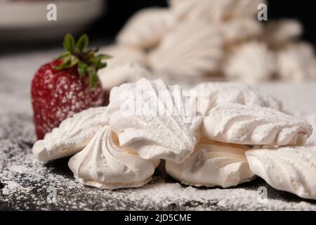 Airy meringues and strawberries on powdered sugar. Stock Photo