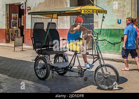 An old man driving Old Havana's most common transportation vehicle, a Bicitaxi Stock Photo
