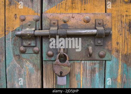 old iron lock on the gate, old wooden planks with shabby paint, close-up detail of a hanging padlock Stock Photo