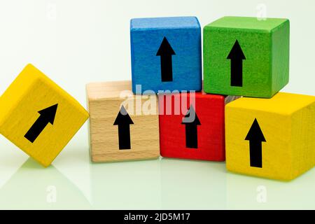 colored wooden blocks with growth arrows arranged in the shape of a pyramid, one block at the bottom showing the way to the top, Stable development co Stock Photo