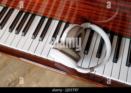 Close-up, white headphones lie on the piano keys. View from above Stock Photo