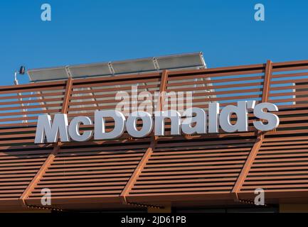Savigliano, Italy - June 16, 2022: McDonald's sign on restaurant on blue sky, McDonald's is the largest hamburger fast food chain Stock Photo