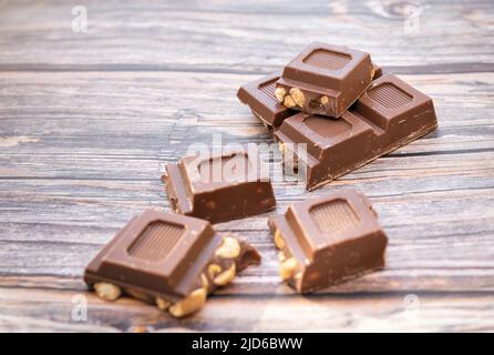 SEVEN SQUARES OF MILK CHOCOLATE AND PEANUTS ON A WOODEN TABLE. COLOR. NATURAL LIGHT. HORIZONTAL. Stock Photo