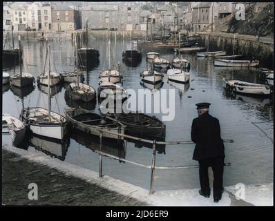 A quiet and placid scene, by the old harbour, where an old Cornish fisherman takes in the scene in the village of Mevagissey, Cornwall, England. Colourised version of : 10154905       Date: 1930s Stock Photo