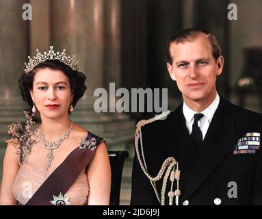 Queen Elizabeth II and Prince Philip, Duke of Edinburgh pictured together in the Grand Entrance in Buckingham Palace in 1954.  The Queen is wearing a yellow tulle evening gown decorated with sprays of mimosa and gold pailette embroidery and is wearing the blue Ribbon and Star of the Garter.  Her necklace was a wedding present from the Nizam of Hyderabad; the tiara also a wedding present from Queen Mary.  The bow brooch and drop earrings are set with diamonds.  The Duke is wearing the uniform of the Admiral of the Fleet. Colourised version of: 10530111       Date: 1954 Stock Photo