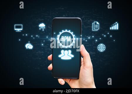 Concept BPM or Business process management. Holographic icons by the phone in the hands of a person. Stock Photo