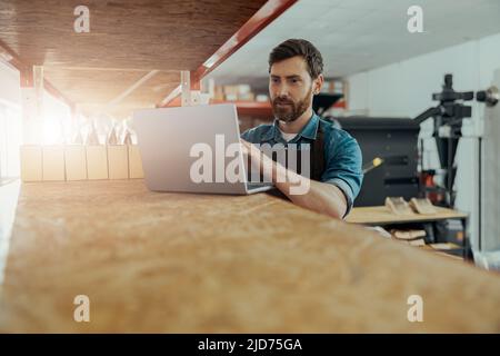 Warehouse worker in uniform standing on coffee small factory with laptop Stock Photo