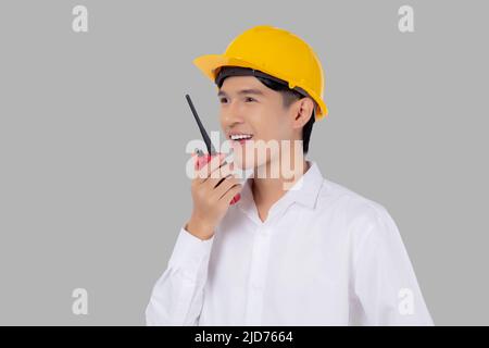 Portrait young asian man is engineer wearing helmet standing and using radio for speak with confident isolated on white background, handsome male is a Stock Photo