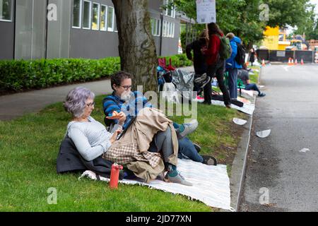 Seattle, Washington, USA. 18th June, 2022. Kristen Dahlquist (left) and Geoff Schemmel relax as they wait for the Fremont Solstice Parade to begin. The iconic, annual parade returned after a three-year hiatus due to the coronavirus pandemic. Credit: Paul Christian Gordon/Alamy Live News Stock Photo