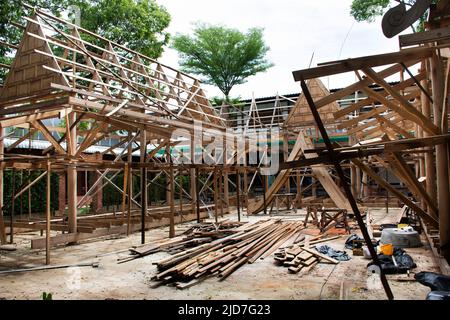 Thai professional carpenter people working and use teak build structure woodwork new building wooden church pavilion in construction site at Wat Sangk Stock Photo