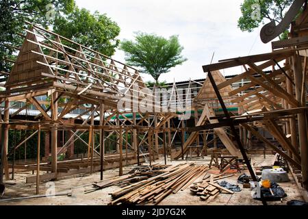 Thai professional carpenter people working and use teak build structure woodwork new building wooden church pavilion in construction site at Wat Sangk Stock Photo