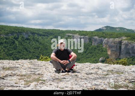 Young male caucasian traveler in red hat and summer hiking outfit