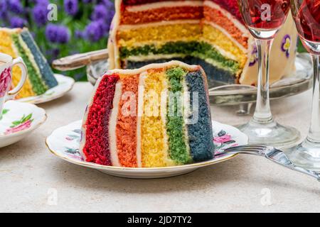 Multi layered rainbow cake set on garden table - outdoor dining Stock Photo