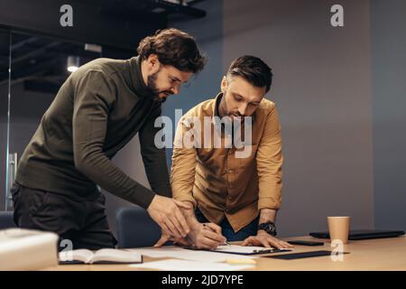 Male colleagues working on startup project, taking notes during brainstorming discussion at modern office Stock Photo