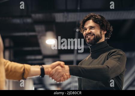 Business partnership. Smiling entrepreneur handshaking with partner after successful negotiations at modern office Stock Photo