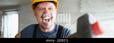 Builder man with a long hammer in his hands Stock Photo