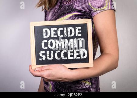 DECIDE COMMIT SUCCEED. Chalk board in a woman's hands. Stock Photo
