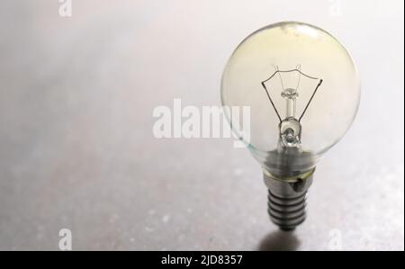 A small incandescent light bulb or lamp on white hard surface Stock Photo