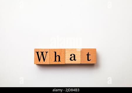 What character. what. Interrogative pronoun. Written on four wooden blocks. White background. Stock Photo