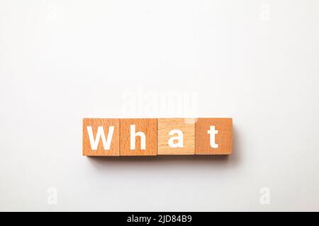 What character. what. Interrogative pronoun. Written on four wooden blocks. White background. Stock Photo