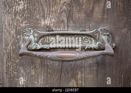 Forged metal hole for mail with Lettres inscription which means Letters in French. Old iron slot for mail on hard wood weathered door close-up Stock Photo