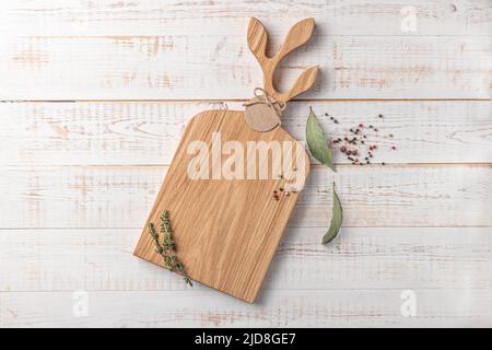 square wooden cutting board with a handle shaped leaves and spices on a white background. mockup with copy space for text, top view Stock Photo