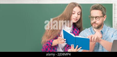 Father and daughter at school, teacher and pupil banner. attentive teen girl and teacher man in high school with workbook and pc at blackboard Stock Photo