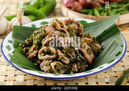 Close Up Cumi Cabe Ijo, Spicy Stir Fry Squid with Green Pepper, Shallot, and Garlic. Served on Enamel Plate on Wooden Table Stock Photo