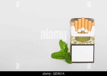 Pack of menthol cigarettes and fresh mint on colored table, Menthol cigarettes top view flat lay. Stock Photo