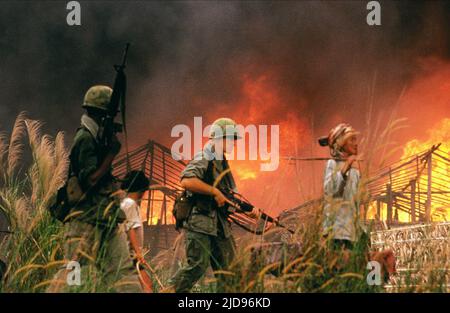 US SOLDIERS PASS BURNING HUTS, CASUALTIES OF WAR, 1989, Stock Photo