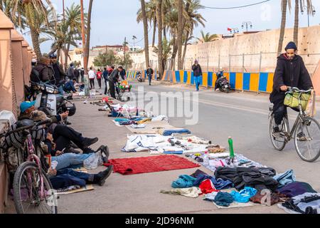 Sellers selling second-hand clothes clothing sold on the ground in the flea market in the street in Marrakech, Morocco Stock Photo