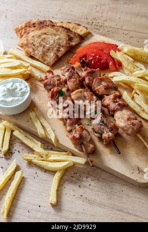 Souvlaki dish, Greek chicken meat food. Grilled skewers and pita bread on wooden table, close up above view, Stock Photo