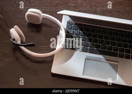 Call center, home office, customer support, help desk. Headset on a laptop, wooden table, view from above, Stock Photo