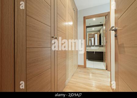 Dressing room with oak wood doors with access to en-suite bathroom with cream marble top Stock Photo