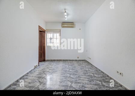 Empty living room with white and gray stoneware floors, wooden carpentry and air conditioning unit Stock Photo