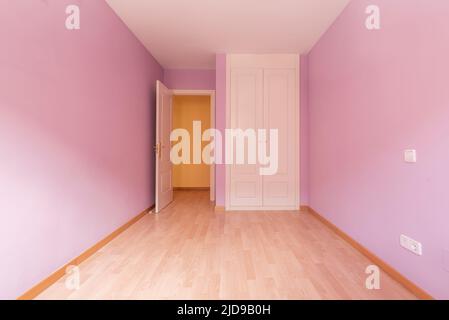 Empty room with built-in two-section white wooden wardrobe, light purple painted walls and light wooden floor Stock Photo